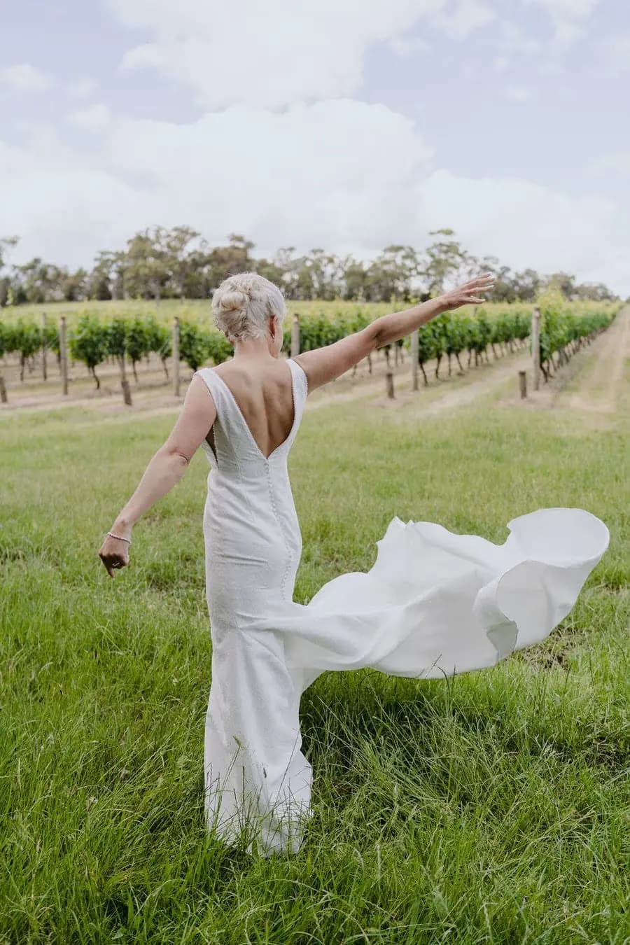 Bride twirls her dress among vineyard rows.