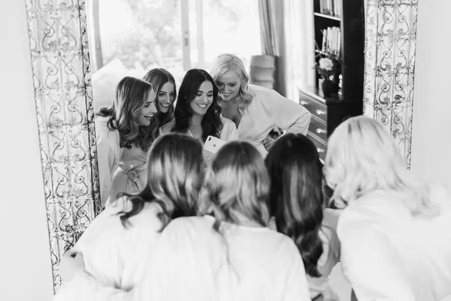 Black and white photograph of women leaning together for a mirror photograph.