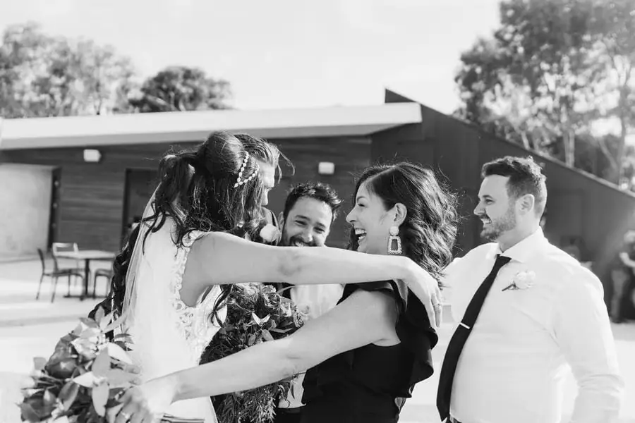 Black and white photograph of the bride greeting guests with an embrace.
