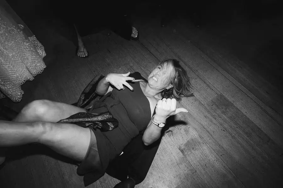 Black and white photograph of a guest laughing while lying on the reception floor.