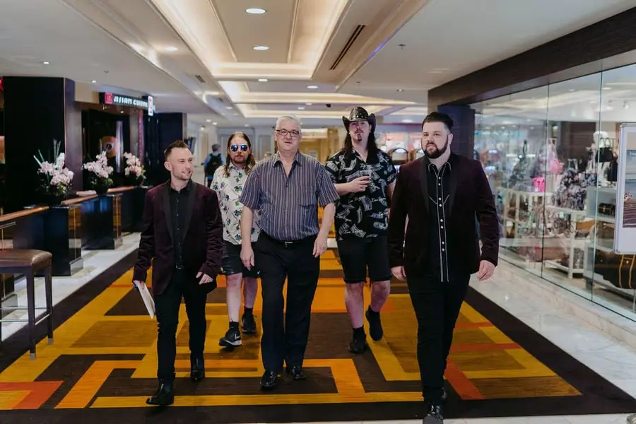 Men walk together along a brightly carpeted indoor corridor.