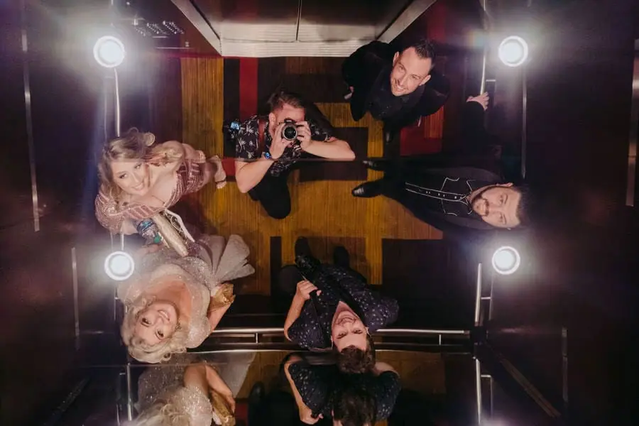 Reflected view of guests and photographers looking upward from inside a lift.