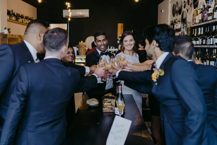 Wedding party raises glasses together for a toast inside a bar.