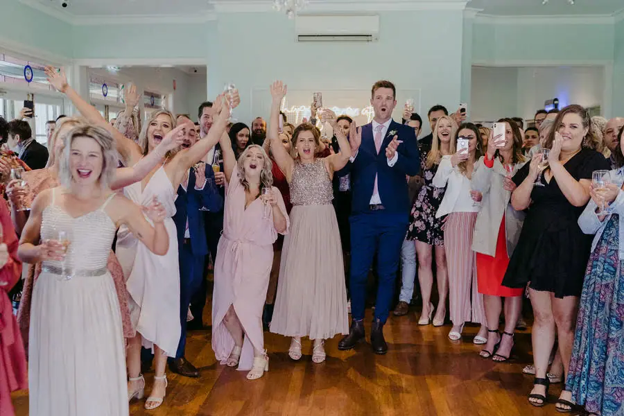 Guests raise their arms and cheer together in the reception room.