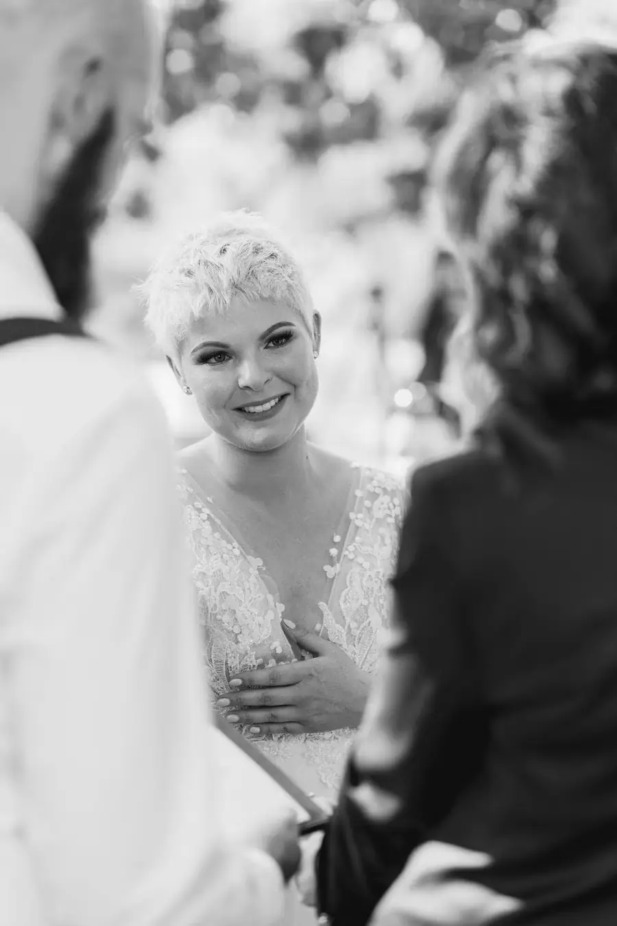 Black and white photograph of the bride smiling toward the groom during the ceremony.