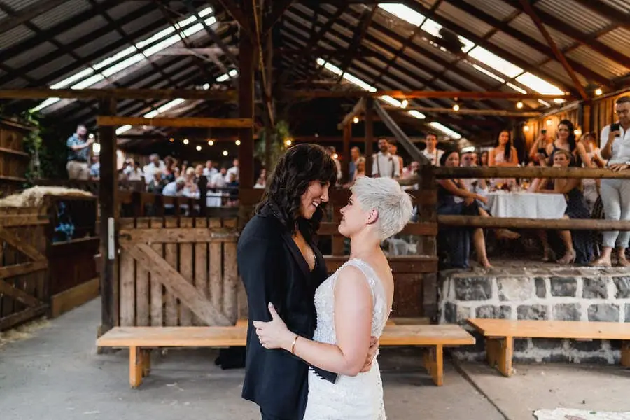 Couple kisses inside a rustic barn reception venue.