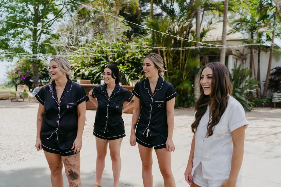 Bride and bridesmaids standing outdoors in sleepwear beneath trees