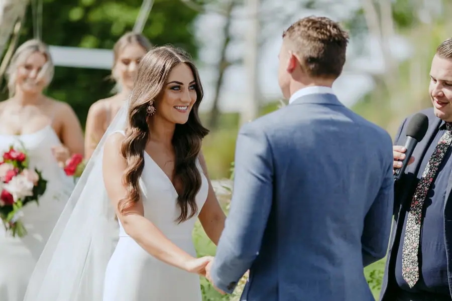 Bride smiling at the groom as they hold hands during the ceremony