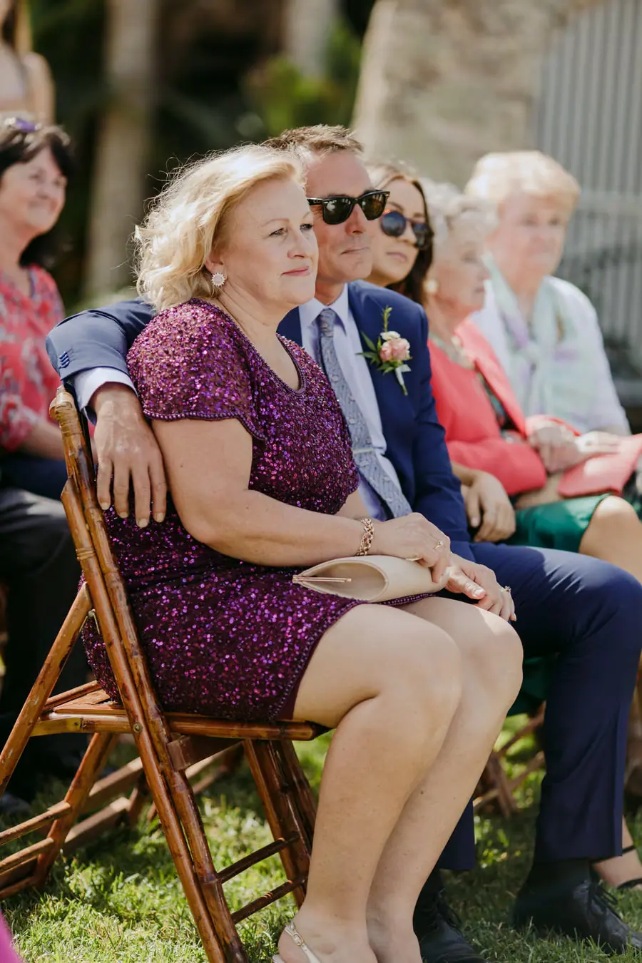 Two guests seated closely together during the outdoor ceremony