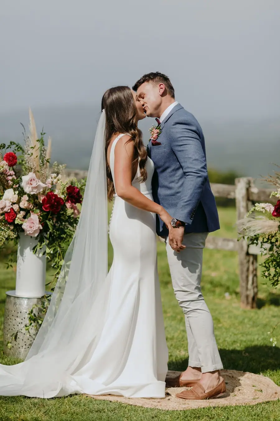 Bride and groom kissing between floral stands at the outdoor ceremony