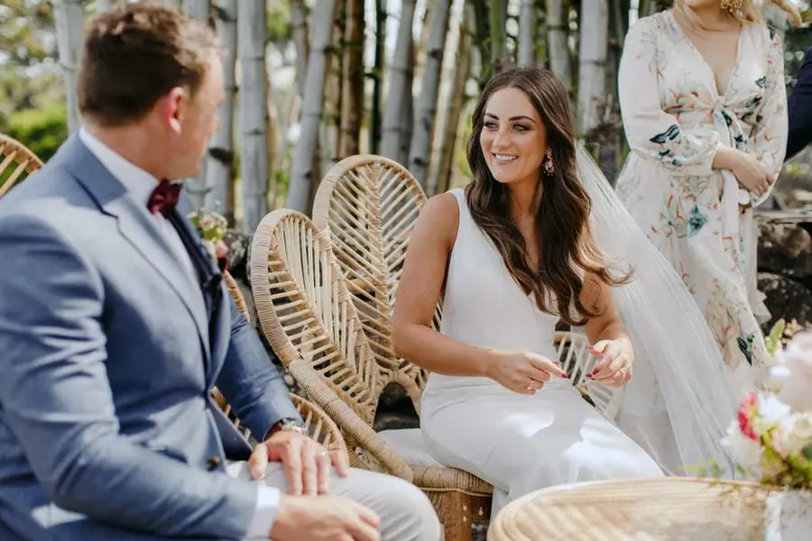 Bride smiling at the groom while they sit in wicker chairs after the ceremony