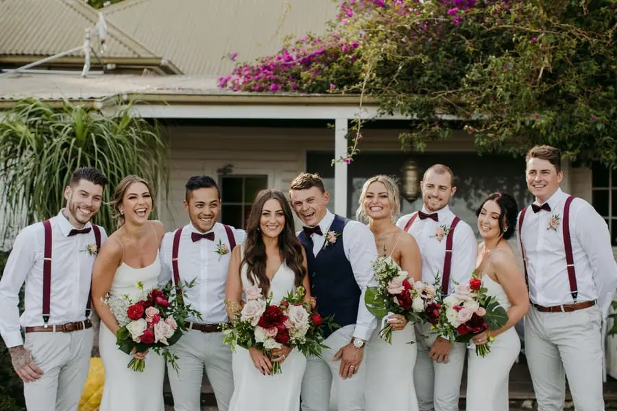 Wedding party posing together outside a white building and garden