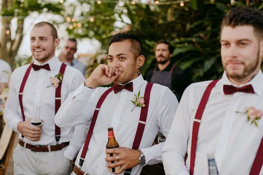 Groomsmen smiling and wiping their eyes while listening to a speech