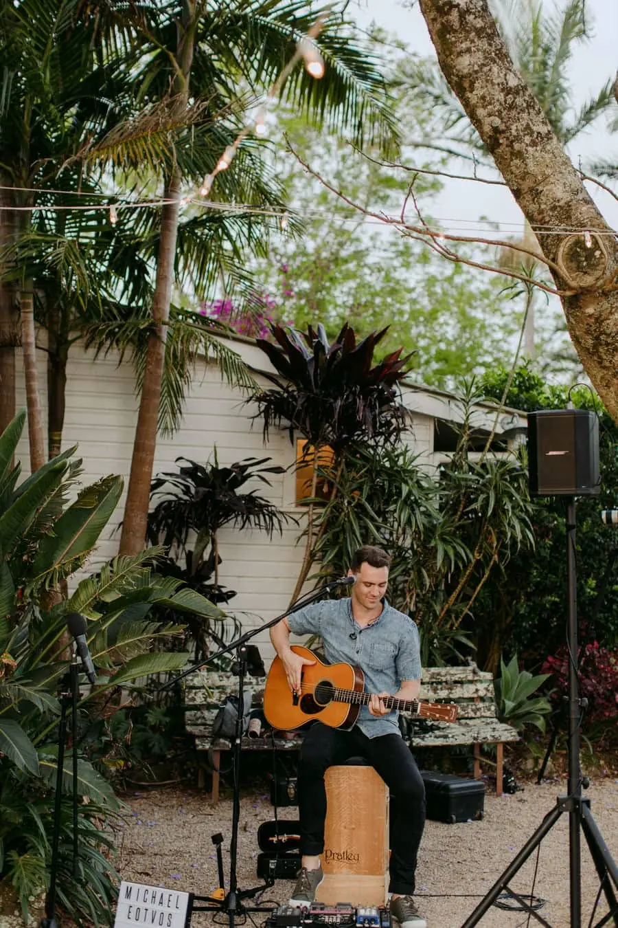 Musician playing an acoustic guitar in a leafy garden