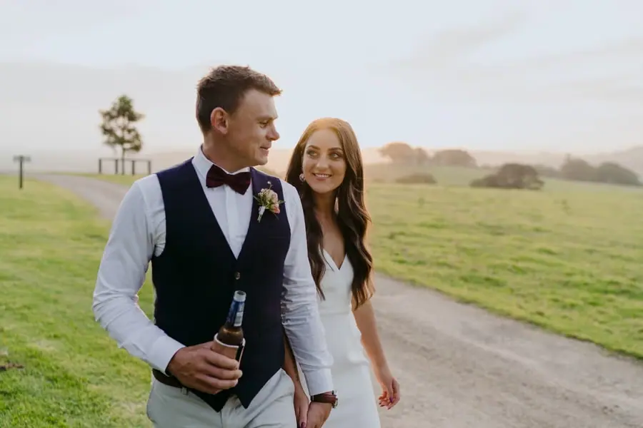 Bride and groom walking together on a country lane at sunset