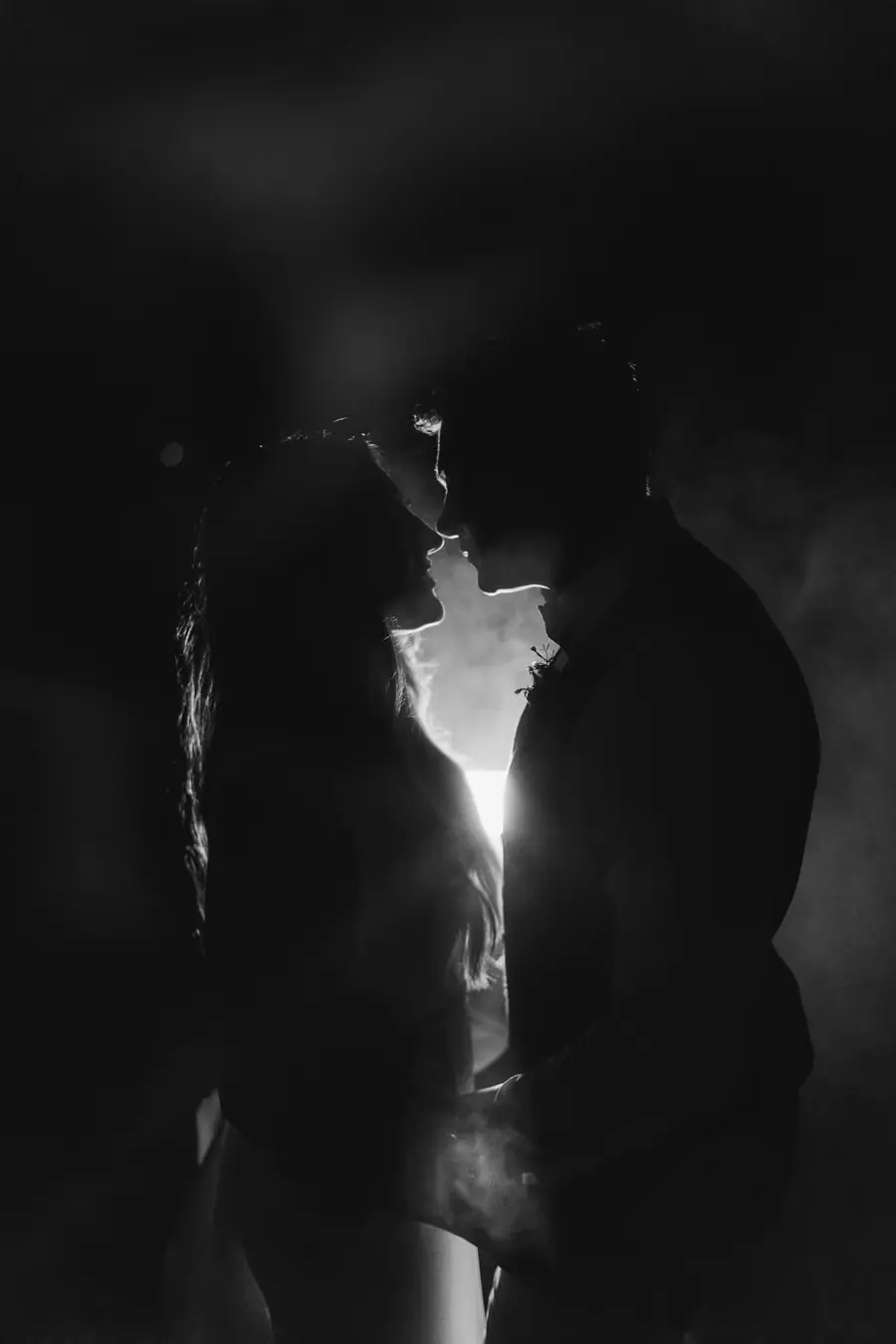 Black and white silhouette of the couple holding hands and leaning toward each other