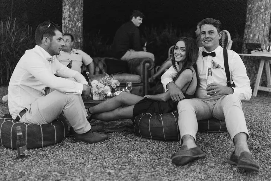 Black and white photograph of guests relaxing on floor cushions outdoors