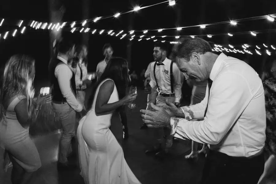 Black and white photograph of guests dancing beneath festoon lights