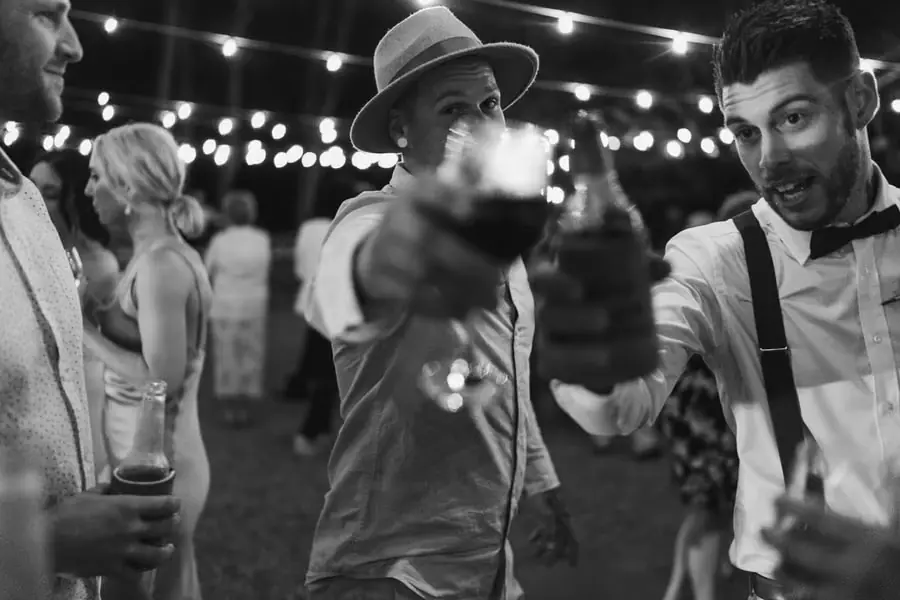 Black and white photograph of two men raising drink bottles toward the camera