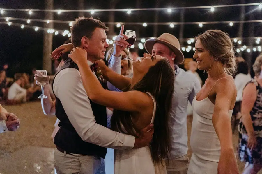 Guests dancing closely together beneath festoon lights