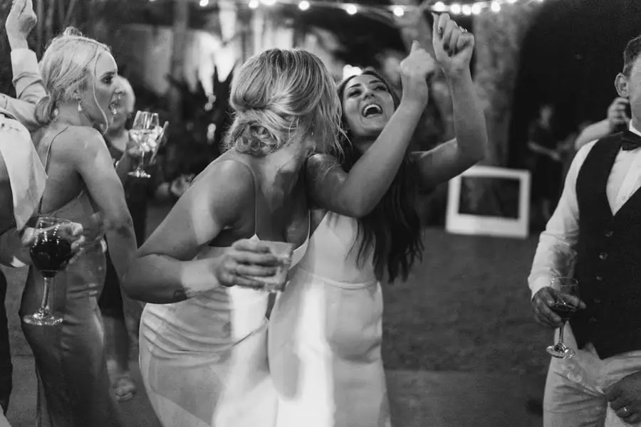 Black and white photograph of women laughing with their arms around each other