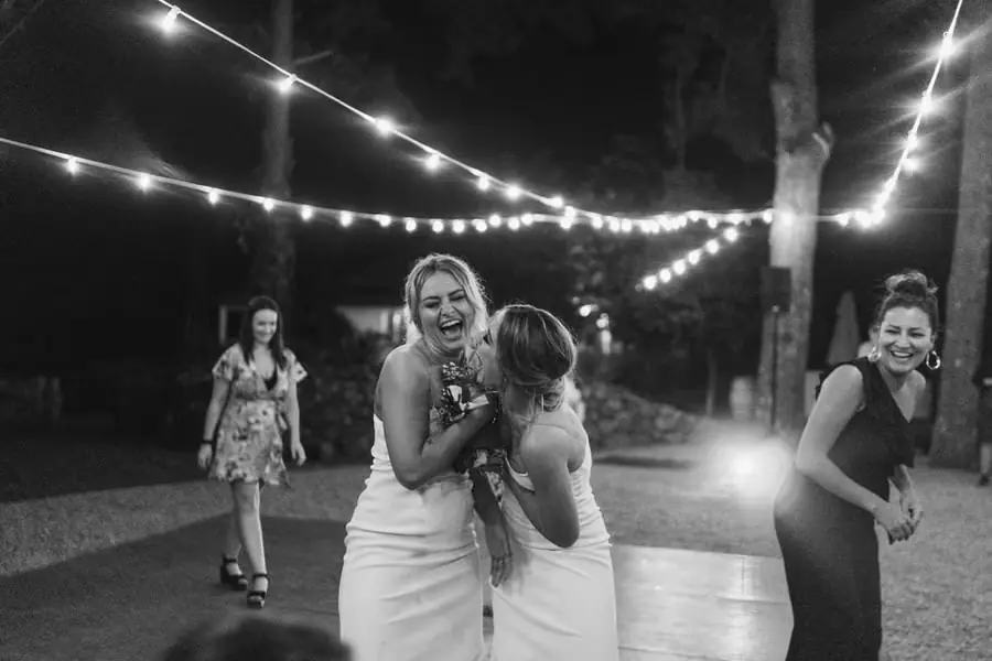 Black and white photograph of women laughing together after the bouquet toss