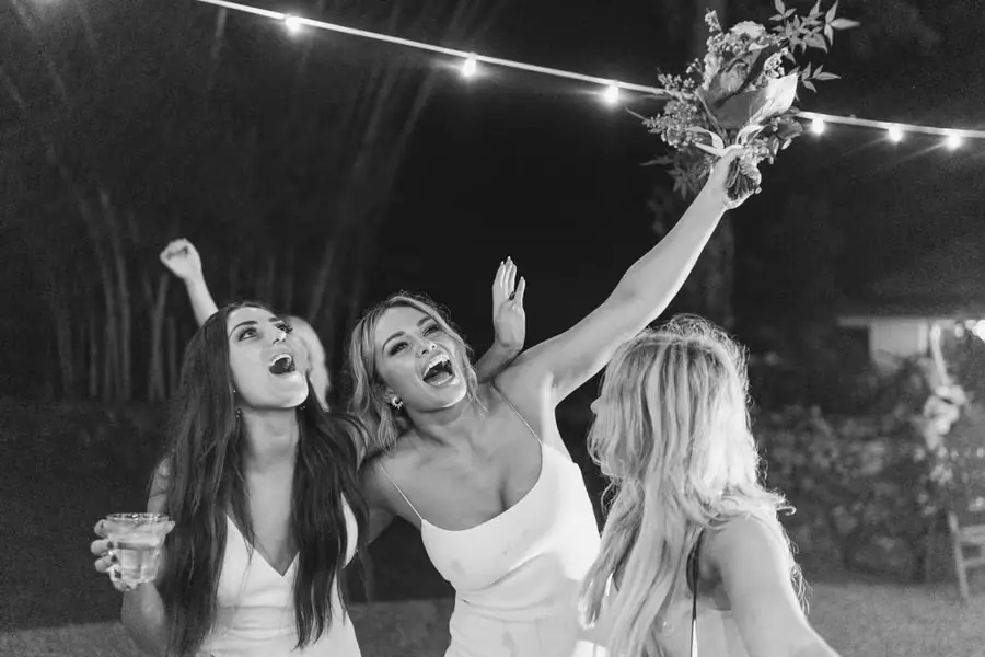 Black and white photograph of three women celebrating with a bouquet raised overhead