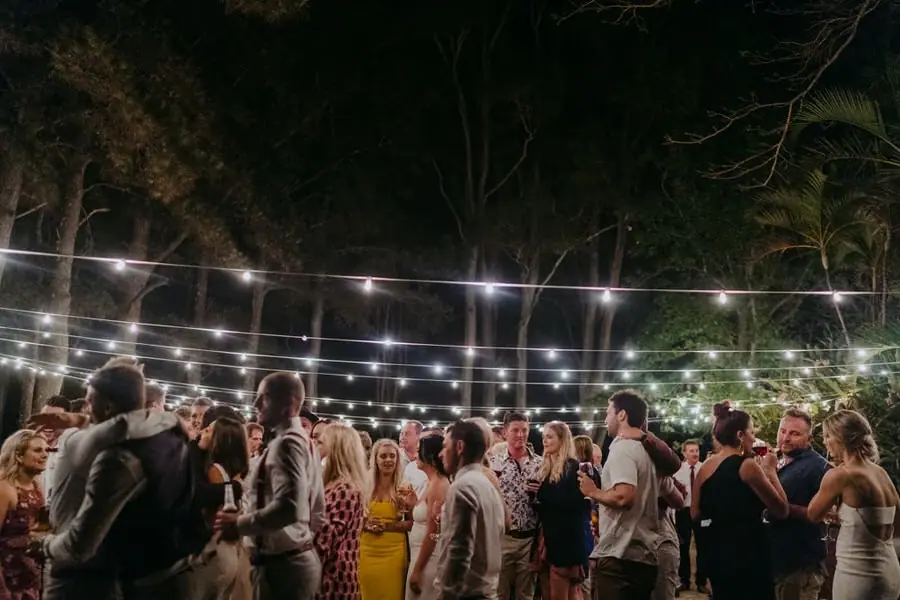 Guests dancing beneath strings of lights at the outdoor evening reception