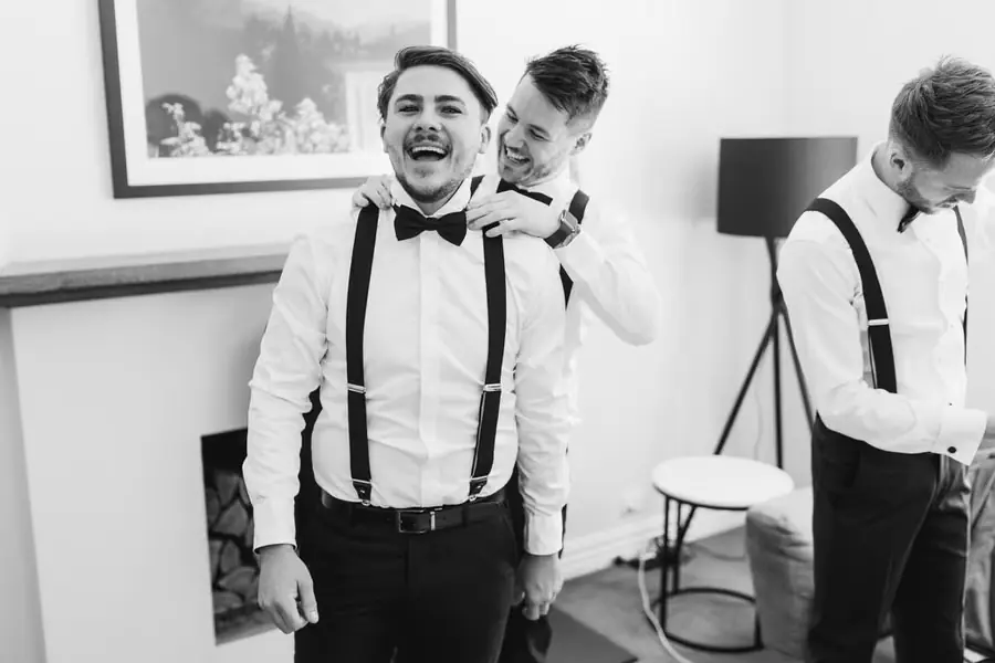 Black-and-white photograph of a friend adjusting a man's collar from behind