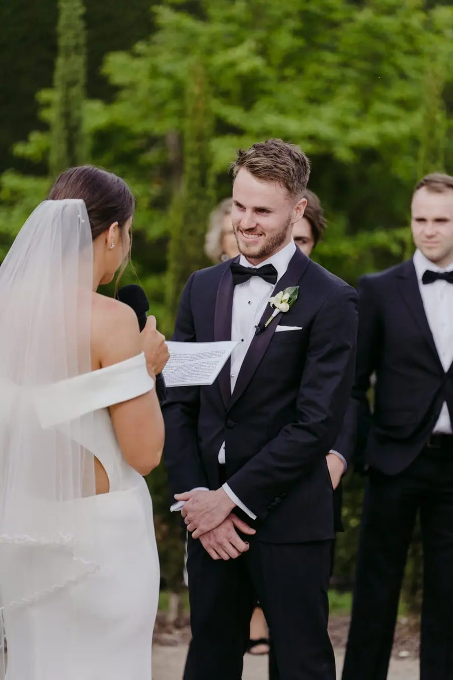 Groom smiling toward the bride while holding her hands during the ceremony