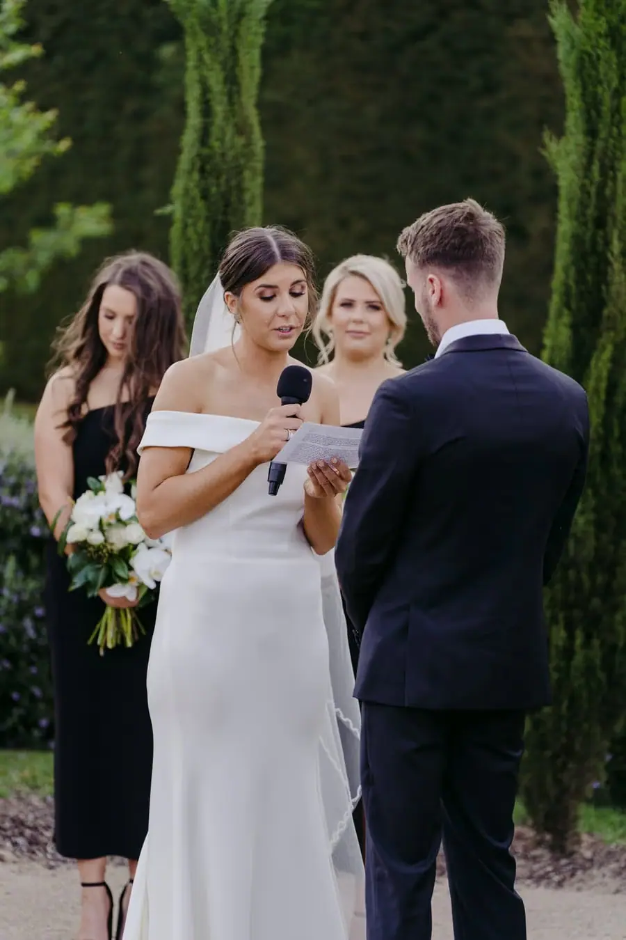 Bride reading vows from paper while holding a microphone
