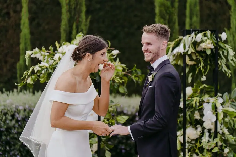 Bride smiling and touching her face while holding the groom's hand