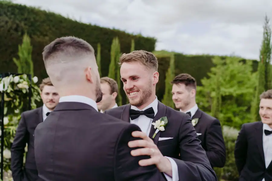 Groom greeting a smiling man after the ceremony