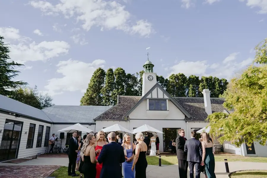 Guests chatting outside a white building with a clock tower