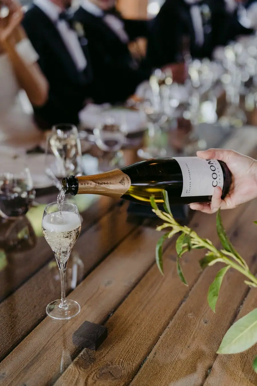 Sparkling wine being poured into glasses at an outdoor table