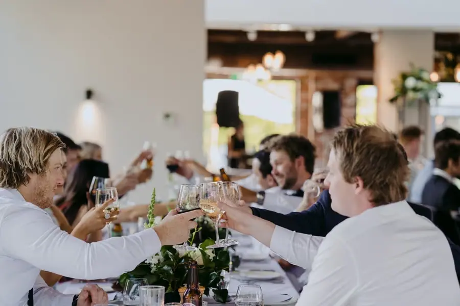 Guests raising wine glasses across the reception table