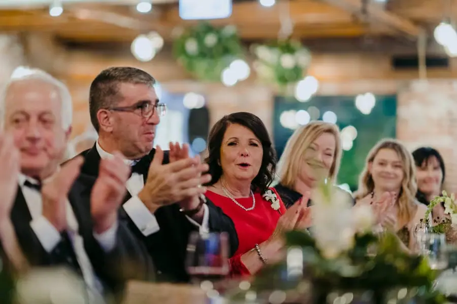 Guests applauding at the reception table beneath warm ceiling lights