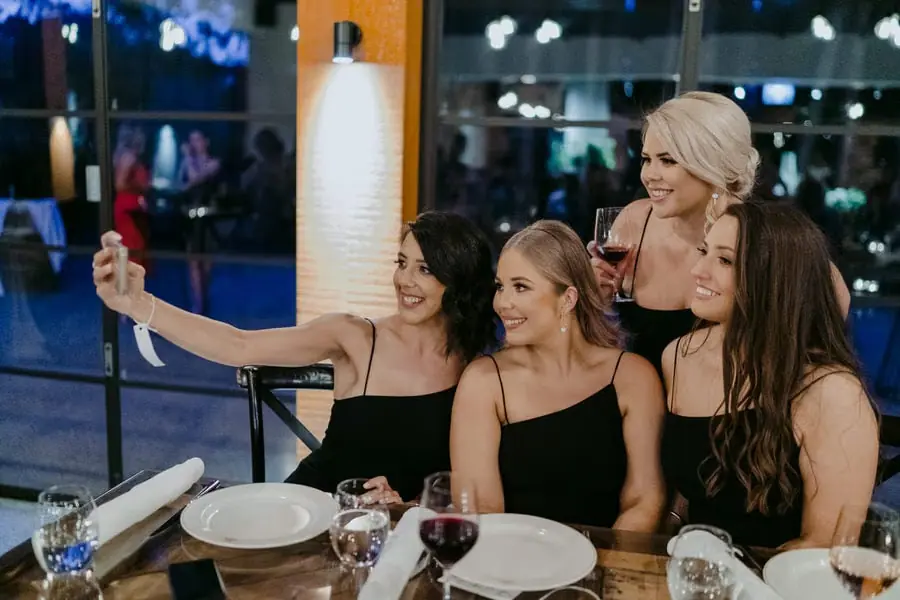 Bridesmaids smiling together for a phone selfie at their reception table