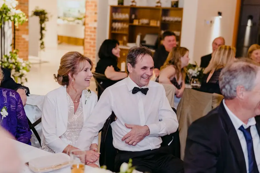 Two guests smiling together among seated reception guests
