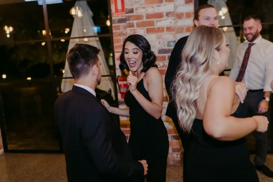 Wedding guests laughing and dancing near the reception windows
