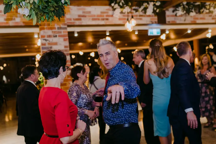 Man pointing toward the camera among dancing wedding guests