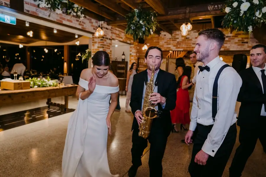 Bride and groom dancing beside a saxophonist in the reception room