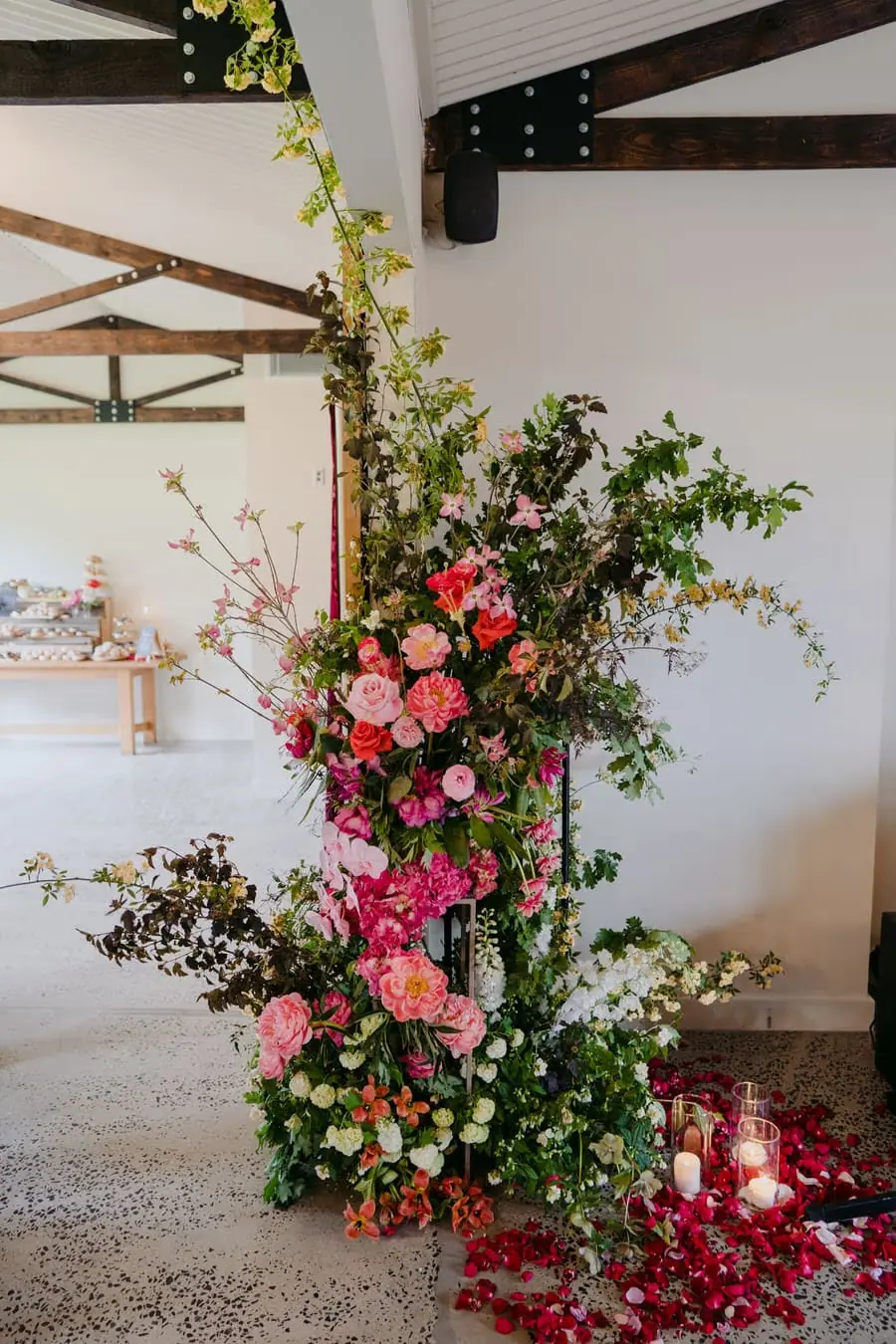 Tall pink flower arrangement entwined around a timber pillar indoors.