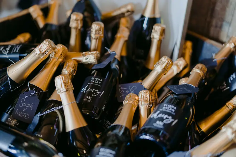 Sparkling wine bottles with gold foil and dark gift tags arranged together.