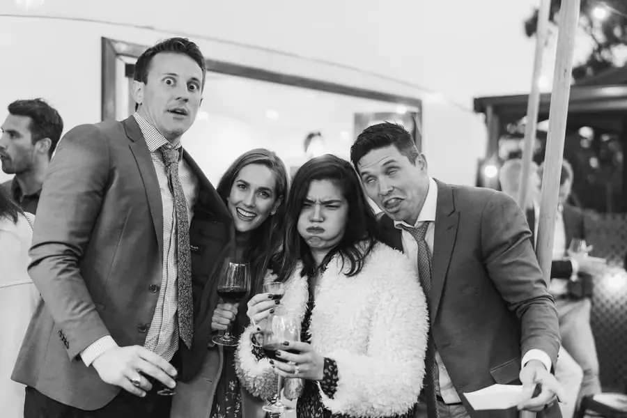 Black-and-white photograph of four guests making playful faces together.