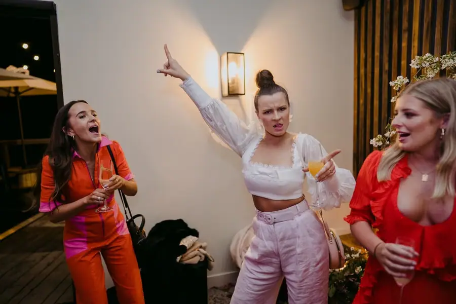 Three women in bright outfits dancing together at the evening reception.
