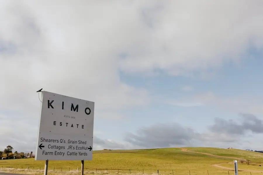 Kimo Estate sign beside open farmland beneath a cloudy sky