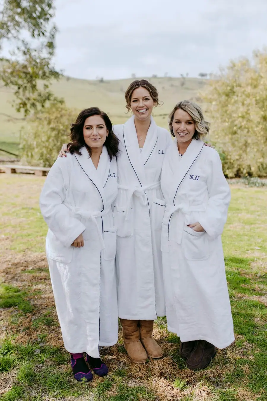 Three women wearing white dressing gowns in a garden