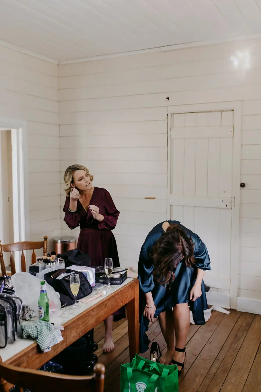 Two women getting ready beside a table covered with bags and clothing