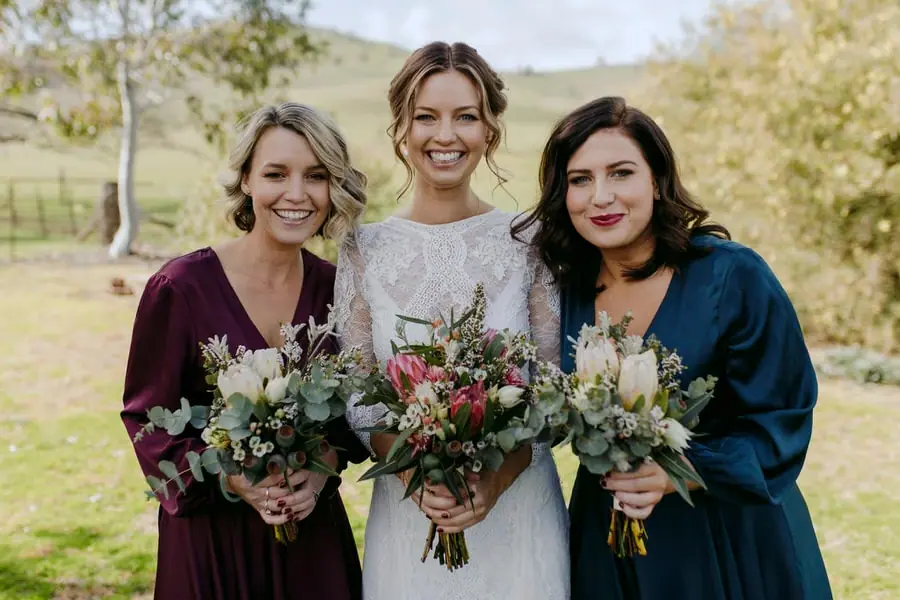 Bride and two bridesmaids holding bouquets in the garden